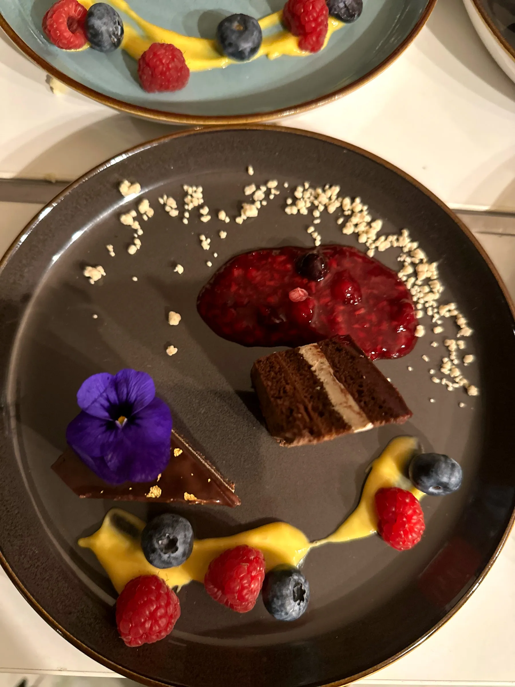 Dessertteller mit Beeren, Schokolade und essbarer Blüte