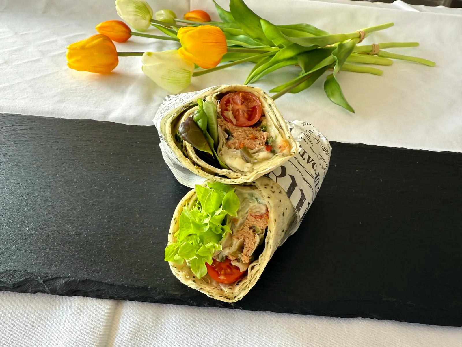 Aufgeschnittener Wrap mit Hähnchen und Salat auf Schieferplatte